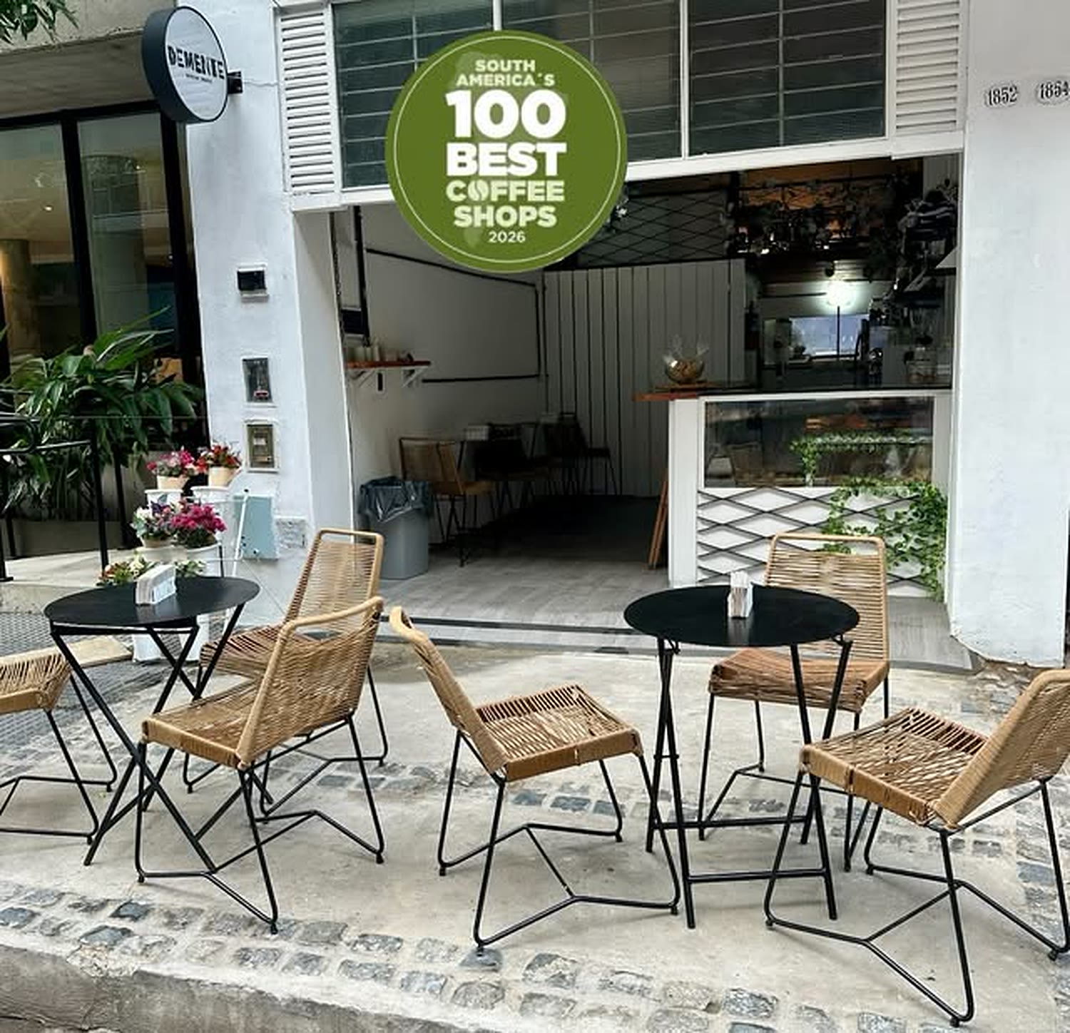Fachada del local de Demente en Ramsay con mesas en la vereda y el sello South America's 100 Best Coffee Shops